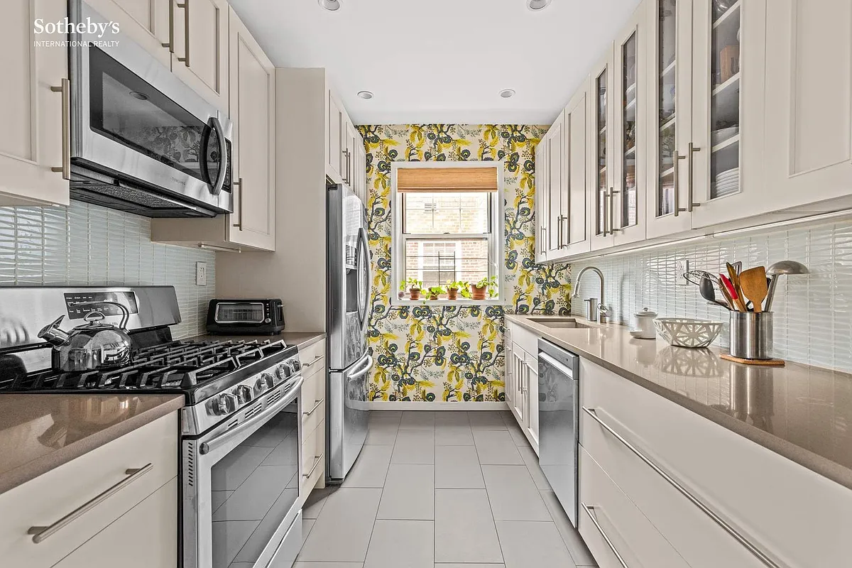 windowed kitchen with white cabinets, stainless steel appliances