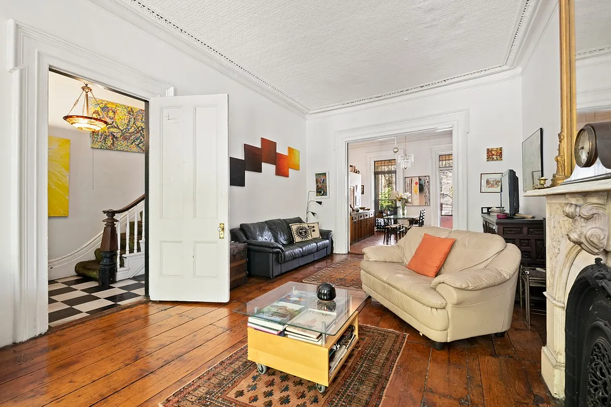 parlor with wide planked floorboards and view into hall with checkerboard floor